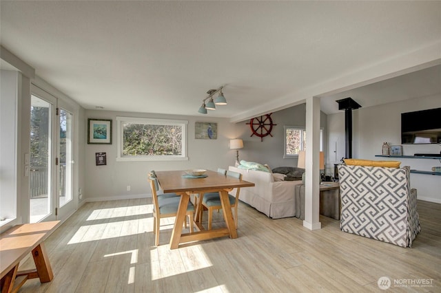 dining area with a wood stove, baseboards, and light wood finished floors