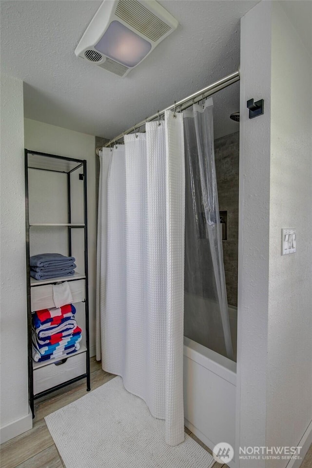 full bath with shower / bath combo with shower curtain, visible vents, a textured ceiling, and wood finished floors