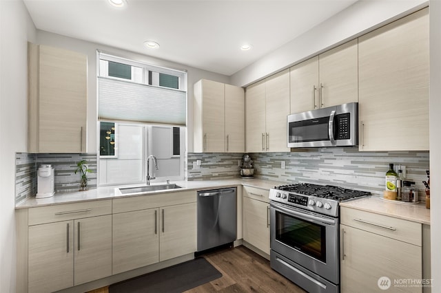 kitchen with stainless steel appliances, dark wood-type flooring, a sink, light countertops, and tasteful backsplash