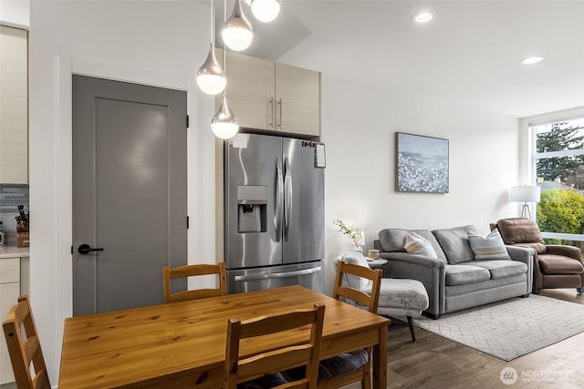 interior space featuring decorative light fixtures, recessed lighting, open floor plan, wood finished floors, and stainless steel fridge