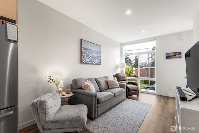 living room featuring a wall of windows, recessed lighting, wood finished floors, and baseboards