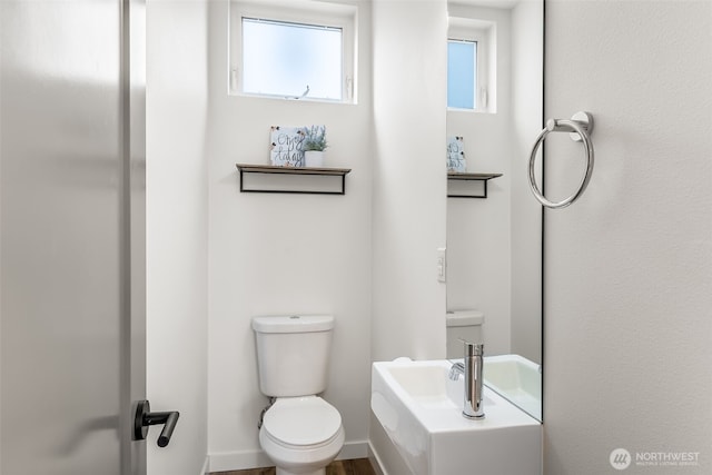 half bathroom featuring baseboards and toilet