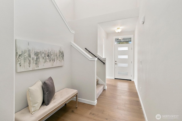 foyer entrance featuring baseboards, stairway, and wood finished floors