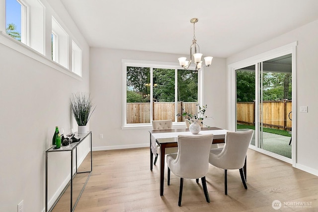 dining area with light wood-type flooring, baseboards, and an inviting chandelier