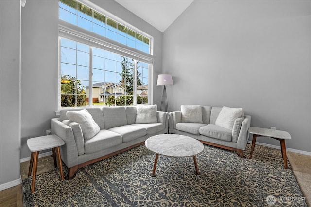 living area featuring high vaulted ceiling and baseboards