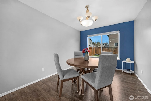 dining room with wood finished floors, baseboards, and an inviting chandelier