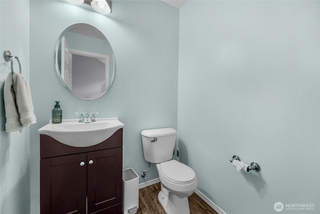 bathroom with toilet, baseboards, wood finished floors, and vanity