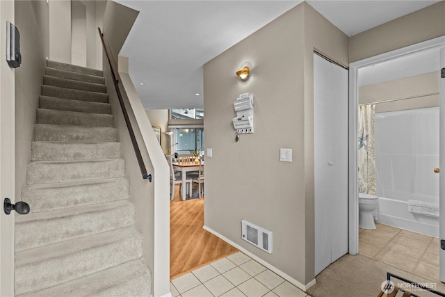 staircase with tile patterned flooring, visible vents, and baseboards