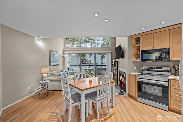 kitchen featuring stainless steel range with electric stovetop, black microwave, light countertops, and light wood-style floors