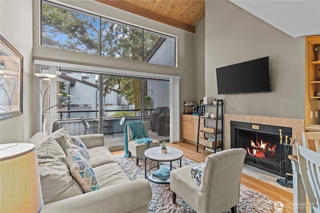 living area with light wood-style floors, wooden ceiling, a fireplace, and high vaulted ceiling