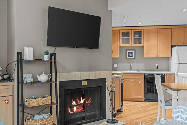 kitchen featuring light wood-style flooring, a sink, black dishwasher, light countertops, and freestanding refrigerator