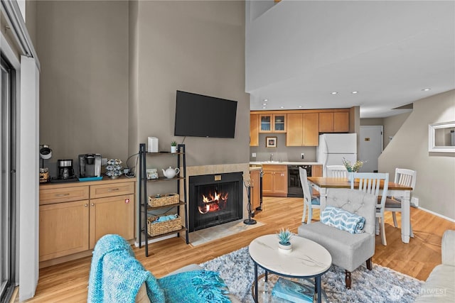 living area with light wood-type flooring, a fireplace with flush hearth, wine cooler, and recessed lighting