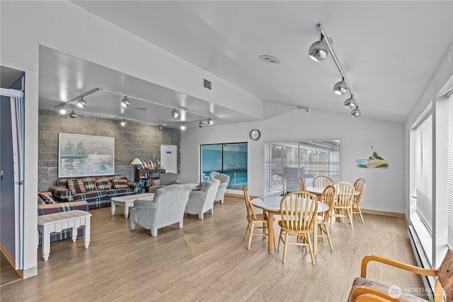 dining space featuring light wood-style floors, visible vents, vaulted ceiling, and track lighting