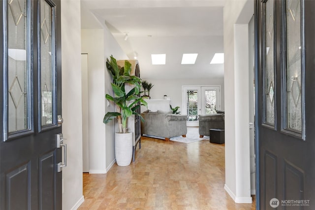 entryway featuring french doors, a skylight, and baseboards