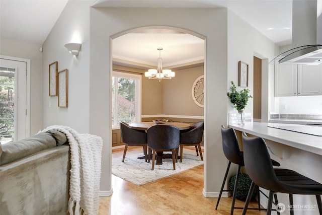 dining space with an inviting chandelier, arched walkways, and ornamental molding