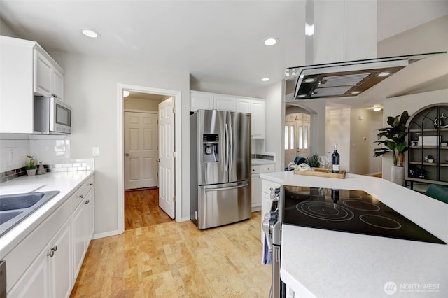 kitchen featuring tasteful backsplash, white cabinetry, stainless steel appliances, light wood finished floors, and light countertops