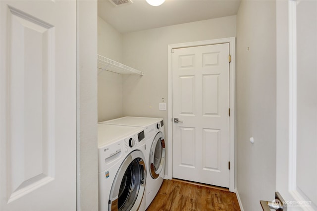 laundry area with washer and dryer, visible vents, wood finished floors, and laundry area