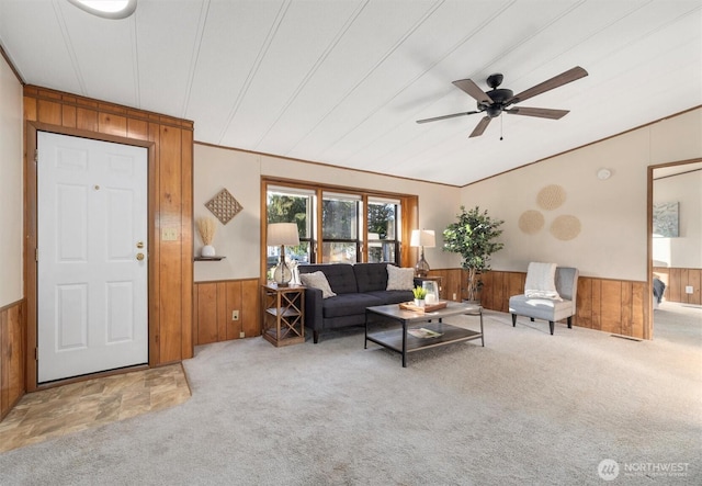 living area with wainscoting, wood walls, carpet, and crown molding