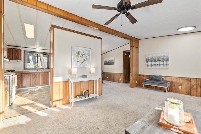 living area featuring light colored carpet, lofted ceiling, a wainscoted wall, and wood walls