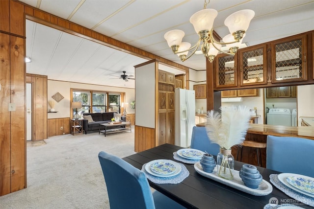 dining room featuring wood walls, wainscoting, light colored carpet, and washer and dryer