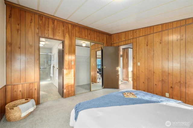 bedroom with a closet, carpet, ensuite bath, and wooden walls