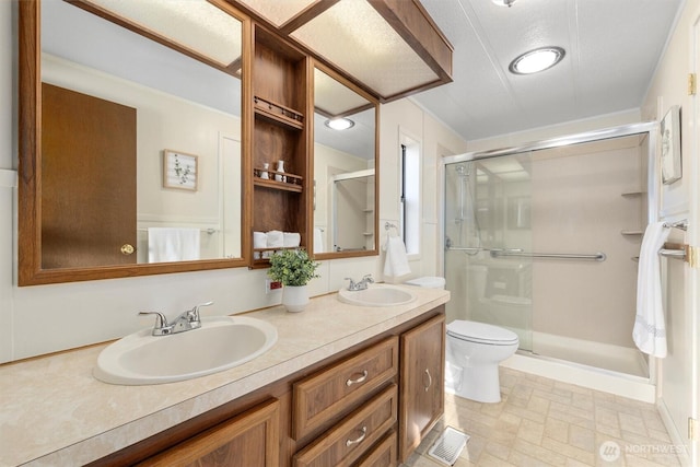 bathroom featuring a stall shower, a sink, toilet, and double vanity