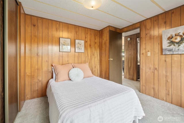 bedroom featuring light carpet and wooden walls