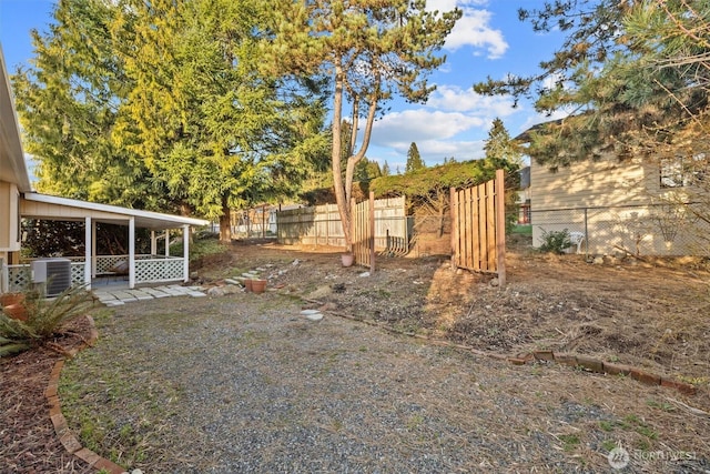 view of yard with central AC and fence