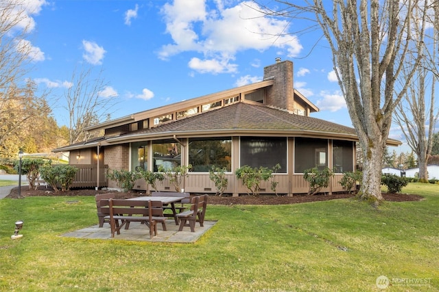 back of property with a yard, roof with shingles, a chimney, and a sunroom