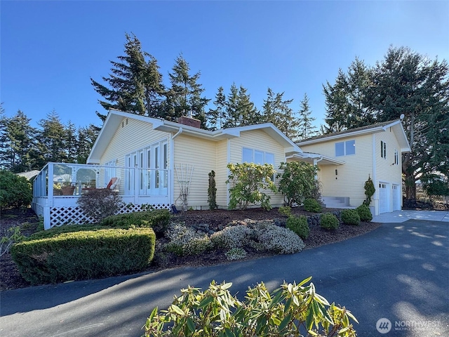 view of property exterior featuring a garage, driveway, and a deck