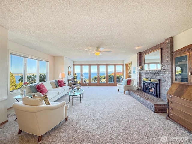 living room with a textured ceiling, carpet, a fireplace, and a healthy amount of sunlight