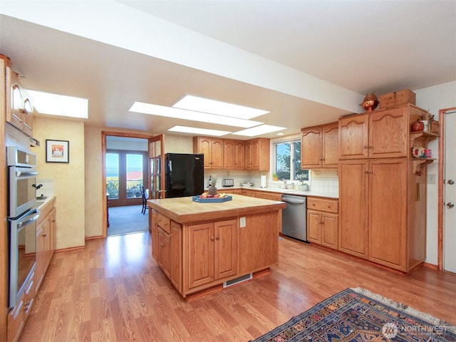 kitchen with light wood finished floors, plenty of natural light, appliances with stainless steel finishes, and a center island