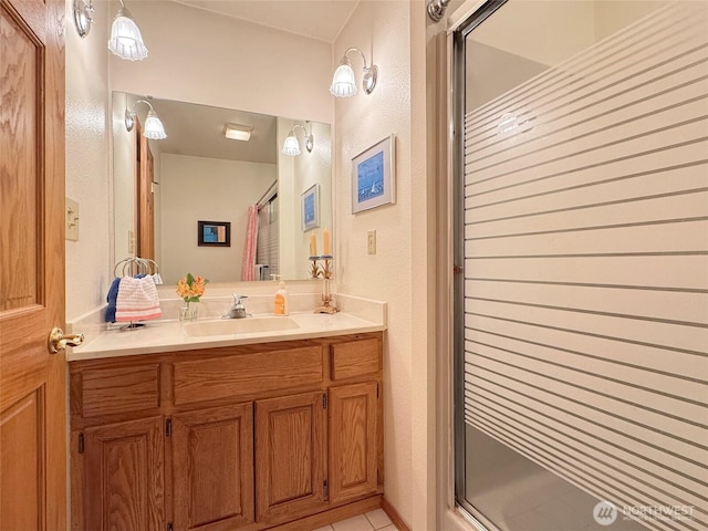 full bathroom featuring a textured wall, tile patterned flooring, a shower with door, and vanity