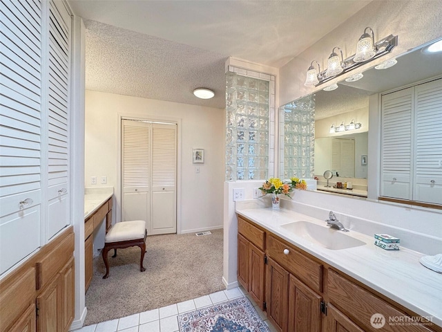 full bathroom with a textured ceiling, tile patterned flooring, visible vents, vanity, and a closet