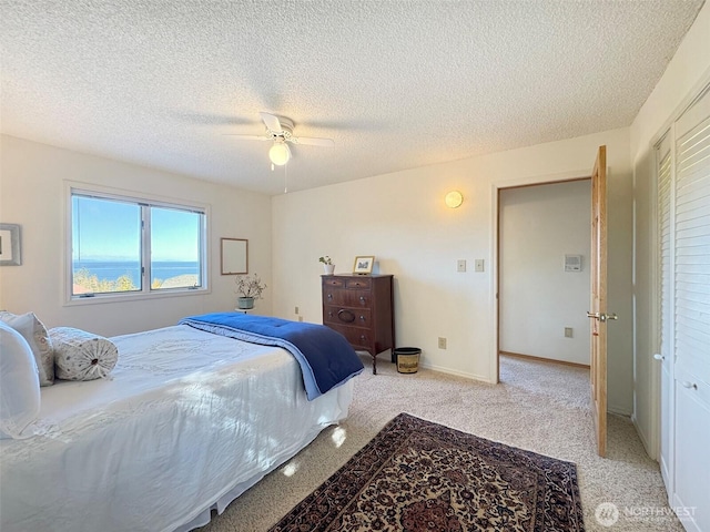 bedroom with baseboards, a textured ceiling, a ceiling fan, and light colored carpet