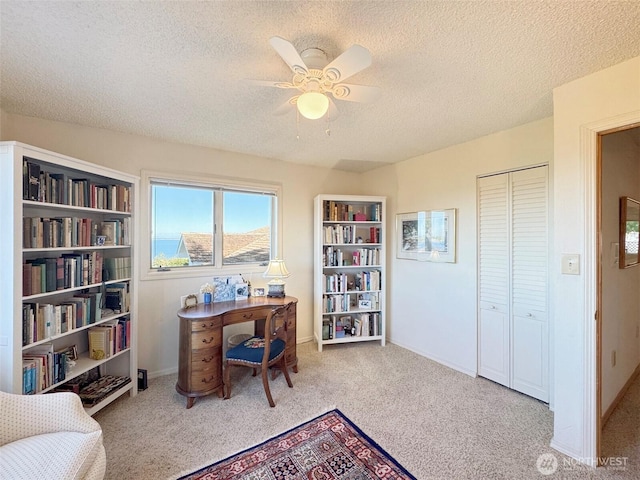 home office featuring carpet, ceiling fan, a textured ceiling, and baseboards