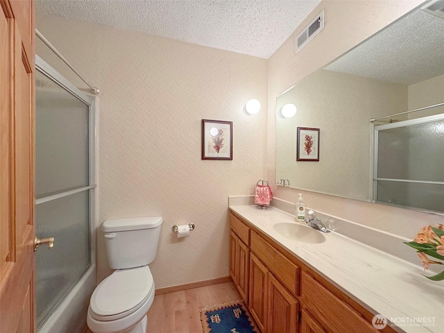 full bathroom featuring a textured ceiling, toilet, wood finished floors, and visible vents