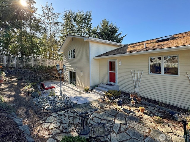 rear view of house featuring entry steps, a patio area, and fence