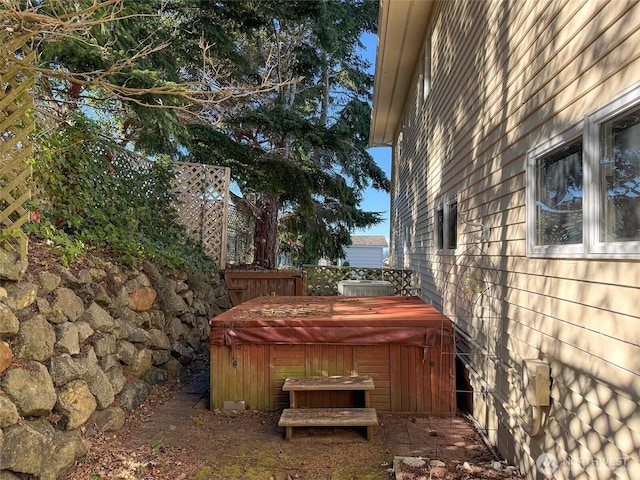 view of yard featuring a hot tub, fence, and cooling unit