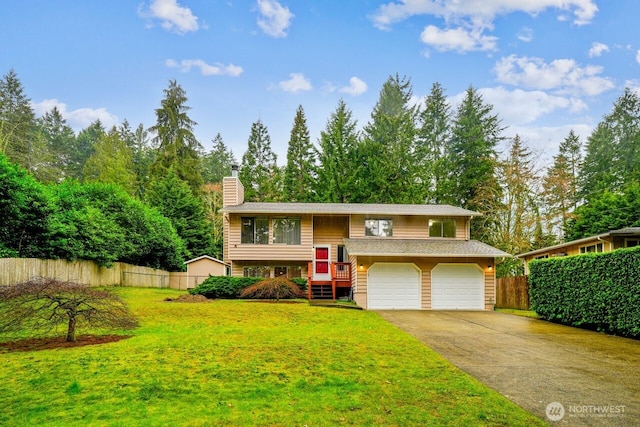 split foyer home with a garage, concrete driveway, fence, and a front lawn