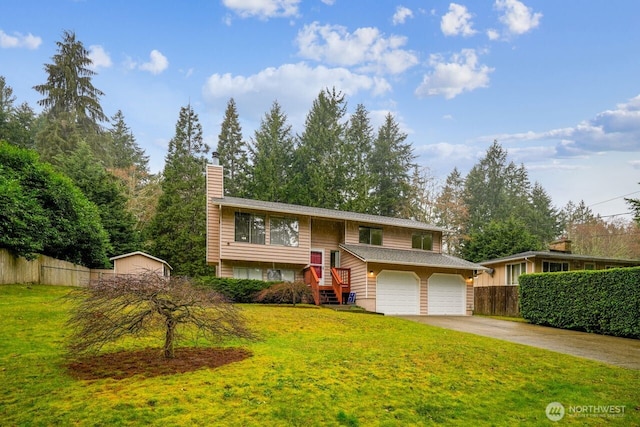 split foyer home featuring concrete driveway, a chimney, a front yard, and fence