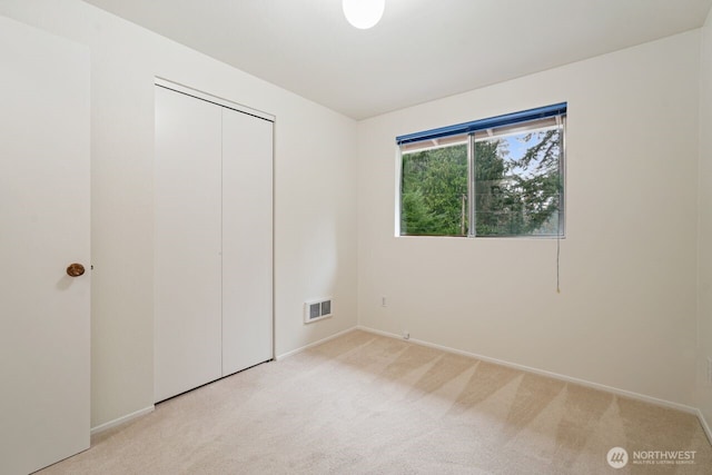 unfurnished bedroom featuring visible vents, a closet, and light colored carpet