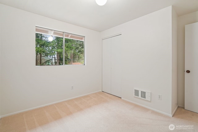 empty room with baseboards, visible vents, and light colored carpet