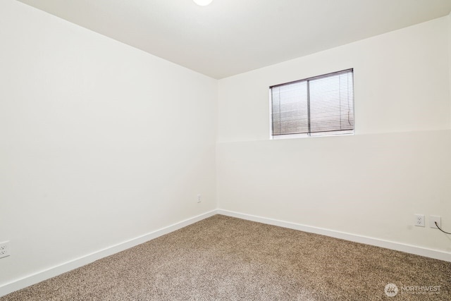 carpeted empty room featuring baseboards