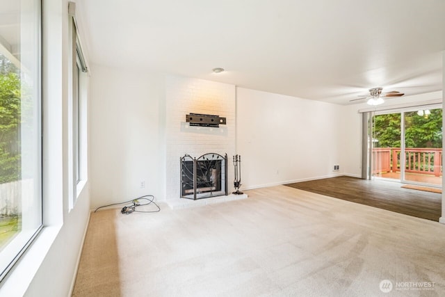 unfurnished living room featuring carpet, ceiling fan, a brick fireplace, and baseboards