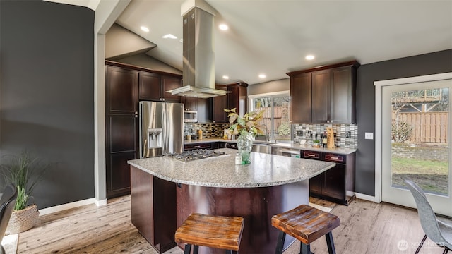 kitchen featuring appliances with stainless steel finishes, light wood-type flooring, island exhaust hood, and decorative backsplash