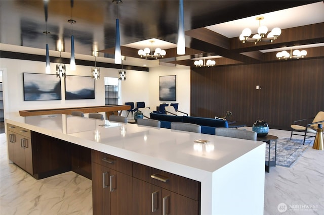 kitchen featuring open floor plan, marble finish floor, wooden walls, and a notable chandelier