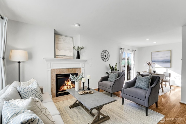 living room with light wood-style floors, a tile fireplace, and recessed lighting