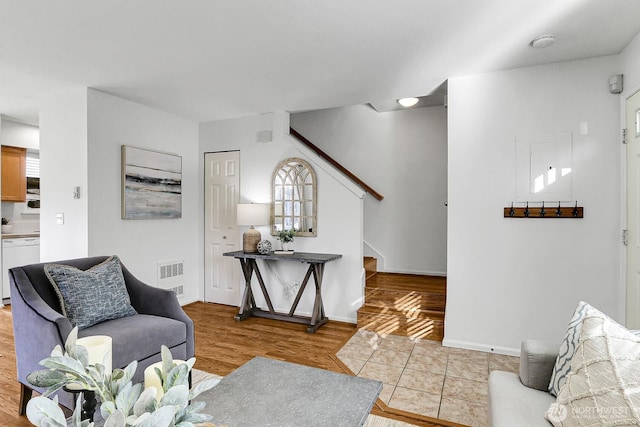 living room featuring visible vents, stairway, baseboards, and wood finished floors