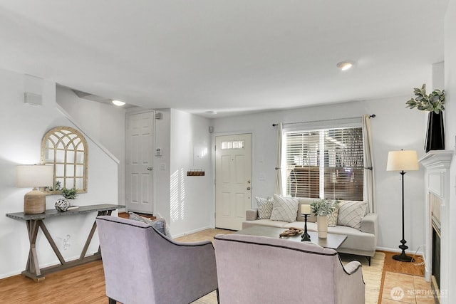 living room featuring a fireplace with flush hearth, light wood-style flooring, and baseboards